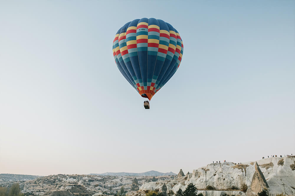 Bunter Heißluftballon schwebt hoch über den Bergen.