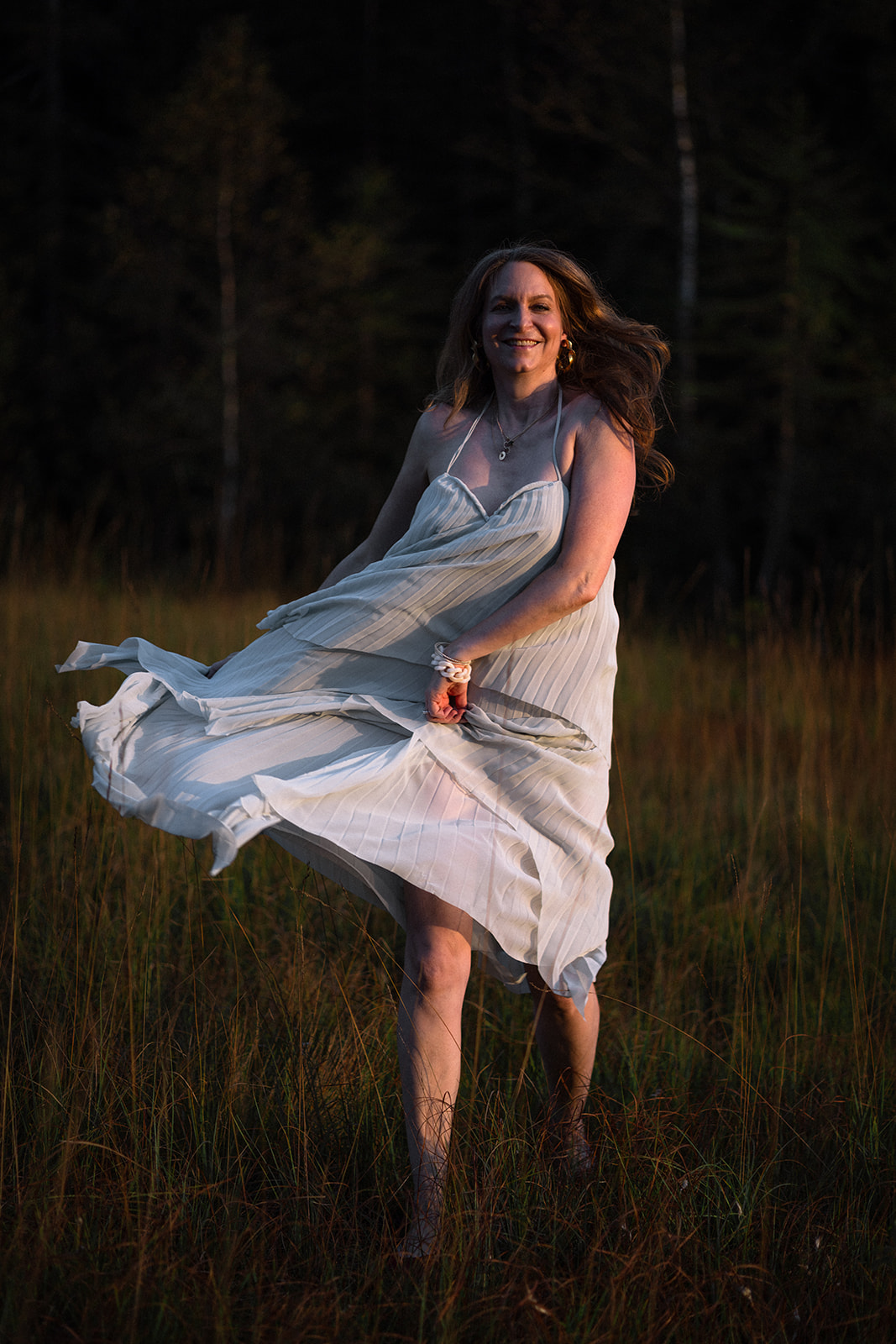 Frau tanzend auf Wiese im fliegenden Kleid.